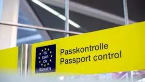 Gelbes Hinweisschild zur Passkontrolle an einem Flughafen mit EU-Symbolik für Reisende.