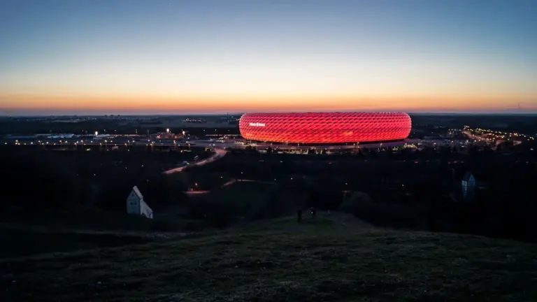 Die Allianz Arena leuchtet in rotem Licht bei Nacht über München.