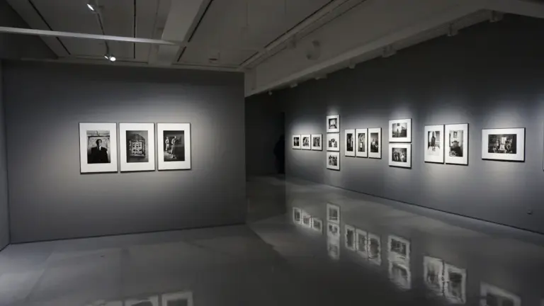 Moderne Kunstausstellung mit gerahmten Werken an grauen Wänden in einem Museum.