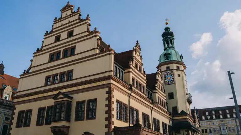 Historisches Rathaus in Leipzig mit markantem Uhrturm unter einem strahlend blauen Himmel.