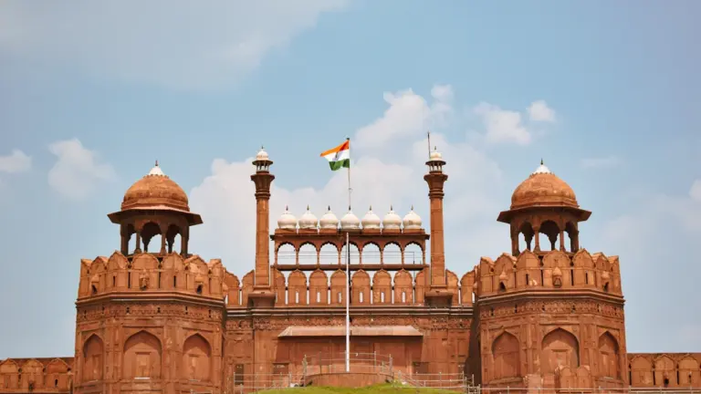 Das historische Rote Fort in Delhi mit der indischen Flagge unter blauem Himmel.