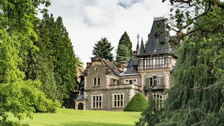 Braunes historisches Gebäude am grünen Feld mit Bäumen im sonnigen Kieler Schloßgarten.
