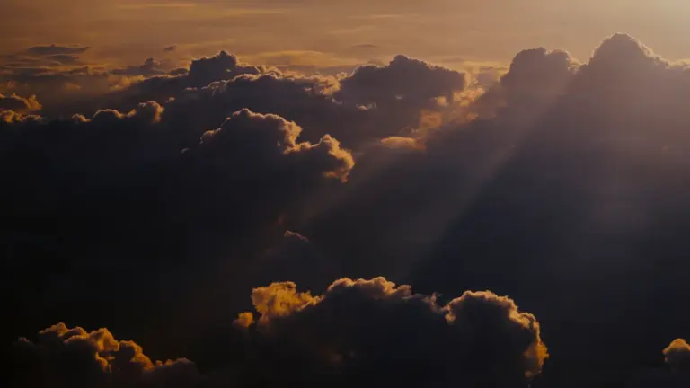 Sonnenlicht bricht durch die Wolkendecke über einer friedlichen Landschaft aus der Vogelperspektive.