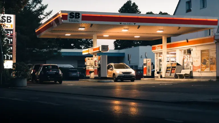 Eine typische deutsche Tankstelle bei Dämmerung mit mehreren parkenden Autos an der Zapfsäule.