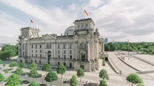 Das historische Reichstagsgebäude unter blauem Himmel mit deutscher Flagge bei Tageslicht.
