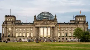 Das Reichstagsgebäude in Berlin bei Tageslicht mit Menschen auf dem Vorplatz.