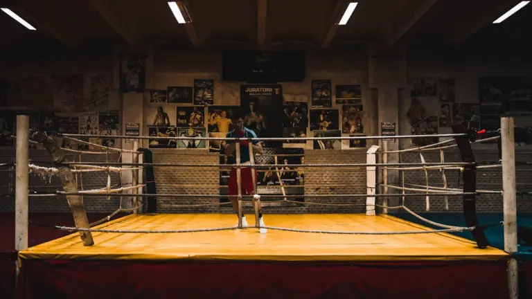 Ein leerer Boxring in einer Trainingshalle mit Plakaten an der Wand im Hintergrund.