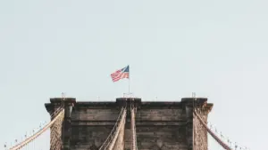 Die Brooklyn Bridge in New York unter einem klaren Himmel mit US-Flagge.