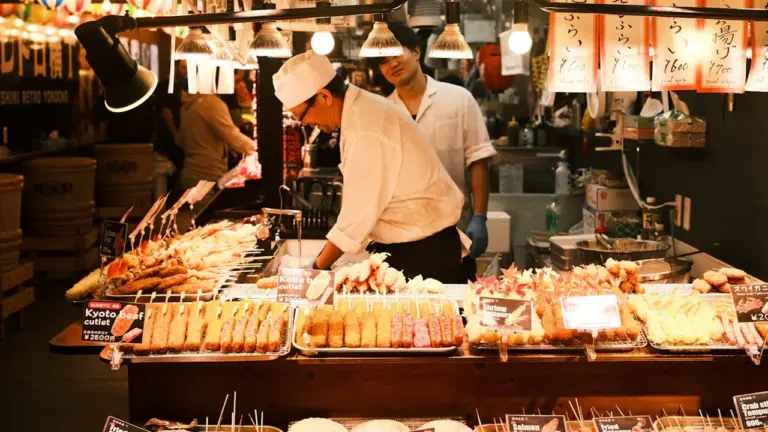 Ein geschäftiger Wochenmarkt mit Verkäufern, die frische Spieße und Speisen zubereiten.