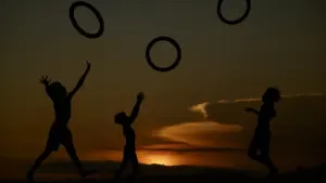Kinder spielen bei Sonnenuntergang und werfen Ringe in die Luft.