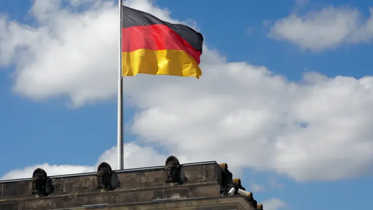 Die deutsche Flagge weht stolz vor blauem Himmel auf dem Reichstagsgebäude in Berlin.