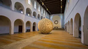 Eine monumentale Kugel aus Holzlatten in einem historischen Kirchenschiff in Bochum.
