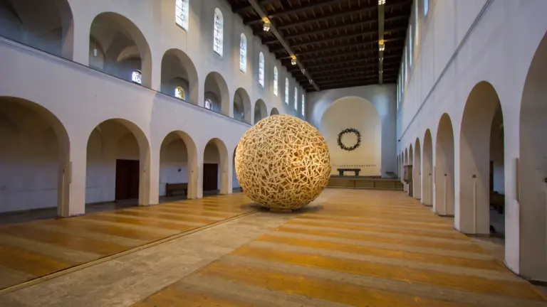 Eine monumentale Kugel aus Holzlatten in einem historischen Kirchenschiff in Bochum.